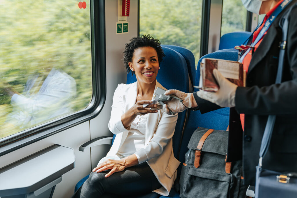 Lächelnde Frau im Zug bei Ticketkontrolle